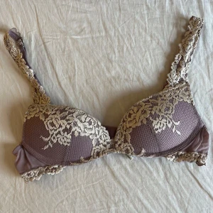 Lila bh med spetsdetaljer från intimissimi  - Säljer en elegant lila bh med vackra spetsdetaljer i beige. Bh:n har justerbara axelband och en klassisk knäppning bak. Perfekt för att känna sig både bekväm och stilfull. Nästa helt oanvänd då den var för liten. Den är inte så mycke lila utan mest smutsrosa.💜🩷
