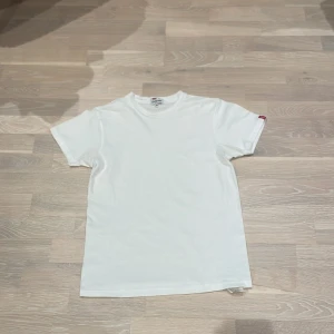 Vit t-shirt från Levi's - Säljer en klassisk vit t-shirt från Levi's i storlek XS. Den har en enkel design med korta ärmar och en liten röd Levi's-logga på sidan. Perfekt för en avslappnad stil.