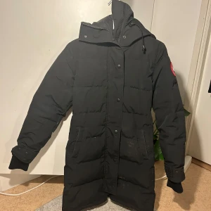Svart dunjacka från Canada Goose - Säljer min äkta Canada Goose-jacka i storlek XS. Jackan är i bra skick och fullt användbar, men har fått en liten fläck på vänstra fickan efter kemtvätt. Annars är den i fint skick! Perfekt för vintern. Äkta pälsen till jackan finns