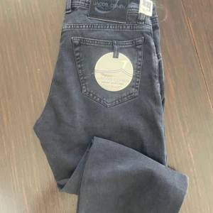 Jacob cohen 688 - Säljer ett par helt nya Jacob Cohen jeans i storlek 32. Det är en exklusiv modell med en snygg mörk tvätt och premiumkänsla. Handgjorda i Italien med riktigt bra material, vilket gör dem både stiliga och bekväma. 	•	Storlek: 32 	•	Färg: Mörkgrå / Svart tvätt •	Skick: Helt nya, aldrig använda