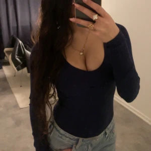 Mörkblå/ marinblå ribbad topp/bodysuit från brave soul - Snygg mörkblå ribbad bodysuit / topp från brave soul med lång ärm och djup v-ringning. Finns ett hål som jag visar näst sista bilden som man ha ett band o knyta med, tappat bort det som kom med. Perfekt för en stilren look. Passar bra till jeans eller kjol för att klä upp sig.