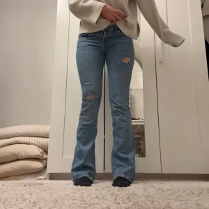 Lågmidjade bootcut jeans - Skitsnygga blå bootcut jeans med slitningar på knäna. Perfekta för en avslappnad stil. De har en klassisk femficksdesign och är tillverkade i ett bekvämt denimtyg. I storlek 36. Skriv gärna vid frågor🥰🥰