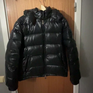 Moncler maya  - Säljer en snygg svart pufferjacka från Moncler maya. Ganska ny använt fåtal gånger inga slitningar. Skick 8,5/10 riktig fett och varmt nu till vinter storlek 3-L men passar M. Intresserad skriv dm😊