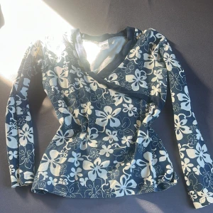 Blommig 2000-talet stil topp - En blå topp med tropiska vita blommor från Lingon&Blåbär. Jättesöt men används inte så mycke längre. 