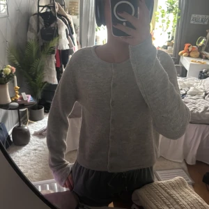 Grå kofta från Gina Tricot - Säljer en mysig grå kofta från Gina Tricot i storlek M. Koftan har en rund halsringning och knappar framtill. Perfekt för kyligare dagar och enkel att matcha med olika outfits.