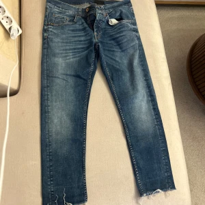 Tiger of Sweden jeans - Snygga blå jeans med en cool slitning vid bensluten. De har en klassisk femficksdesign och en knappgylf. Perfekta för en avslappnad stil.