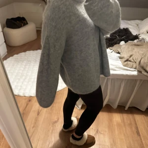 Grå stickad tröja från H&M i mohair - Mysig grå stickad tröja från H&M i storlek L. Perfekt för kyliga dagar med sin mjuka och bekväma passform. Tröjan har långa ärmar och en rund halsringning. Använd 1 gång