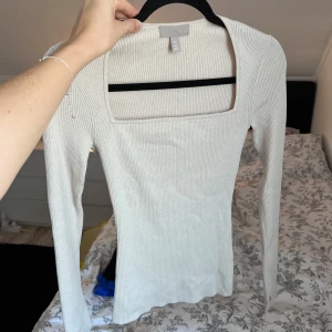 Beige ribbad tröja från H&M - Säljer en stilren beige ribbad tröja från H&M med fyrkantig halsringning. Tröjan har långa ärmar och är perfekt för en chic vardagslook. Passar bra till både jeans och kjol. Använd 2-3 gånger. Önskar du veta exakta mått? Tveka inte att höra av dig!