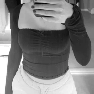 Svart offshoulder topp - Säljer en svart offshoulder topp med långa ärmar och tight passform. Toppen har en croppad längd och en liten volangkant längst ner. Perfekt för att lyfta vilken outfit som helst!