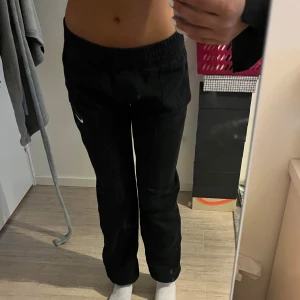 Svarta mjukisbyxor från Nike - Säljer ett par svarta mjukisbyxor i Nike i storlek XS från JD. Byxorna har resår i midjan, raka ben och en vit Nike-logga på ena låret. Perfekta för en avslappnad stil och superbekväma att ha på sig.