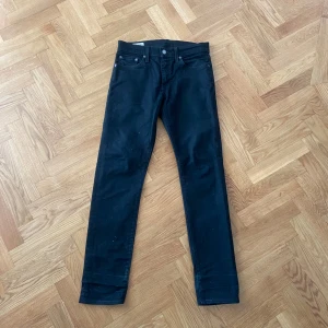 Svarta Levi's 512 jeans - Säljer ett par svarta Levi's 512 jeans med klassisk femficksdesign och slim fit. Byxorna har knapp- och dragkedjegylf samt Levis Premium-märke i midjan. Perfekta för dig som gillar en stilren look.