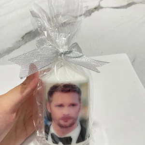 Ljus med en bild eller valfria ord  - Det här är inte en bok, utan ett ljus med ett foto av en man i kostym tryckt på ytan. Ljusen är inslagna i cellofan med en silverfärgad rosett. Ingen bokinformation finns att extrahera från bilderna.