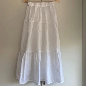Vit långkjol - Säljer en vit långkjol med volangdetaljer och resår i midjan. Från Gina tricot i storlek S