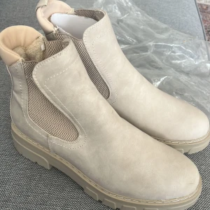 Skor  - Säljer ett par snygga beige chelsea boots med grov platt sula och elastiska partier på sidorna. Skorna har rund tå och är perfekta för dig som vill ha en stilren och modern look till vardags. 