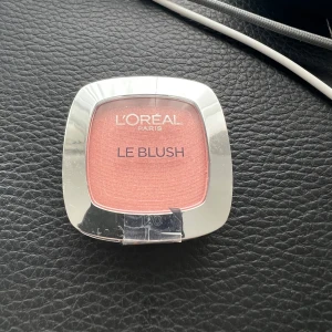 L'Oréal Paris Le Blush 120 Rosewood Pink - Ljusrosa puderrouge från L'Oréal Paris i nyansen 120 Rosesantal/sandalwood Pink. Kommer i en kompakt dosa med spegel och medföljande borste, perfekt för att ge kinderna en fräsch och naturlig färg. 5g nyskick, oöppnad! 