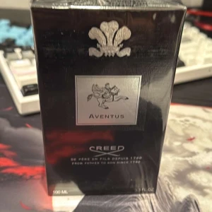 Creed Aventus Eau de Parfum 100ml - Lyxig parfym från Creed, Aventus, i svart och silver kartong. Flaskan rymmer 100 ml och doften är känd för sina fruktiga och träiga noter. Märket är exklusivt och parfymen passar dig som vill sticka ut med en ikonisk doft.