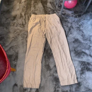 Beiga linnebyxor med resårmidja - Säljer ett par beiga linnebyxor från 157 med resår i midjan och raka ben. Byxorna har en avslappnad passform och är perfekta för varmare dagar. Fickor i sidorna och mjukt, luftigt material.