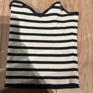 Randig ribbad tubtopp - Säljer en stilren randig tubtopp i svart och vit. Toppen är ribbad vilket ger en skön passform och den är perfekt för varmare dagar. Enkelt att matcha med olika outfits!