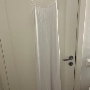 Gullig vit långklänning från hm - Original pris 149, mitt pris 99. Aldrig använd prislappen är på. Klänningen är ärmlös med smala axelband och har en enkel och elegant design. Perfekt för varma dagar eller som en bas i garderoben. 