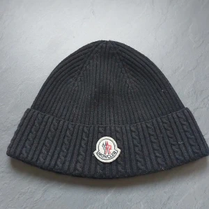 Svart mössa från moncler - Svart moncler mössa med nyttskick.