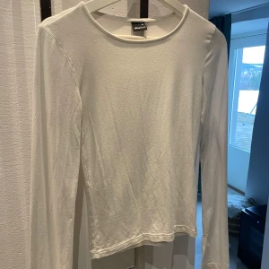 Vit långärmad topp från Gina Tricot - Säljer en stilren vit långärmad topp från Gina Tricot i storlek XS. Perfekt basplagg med rund halsringning, tillverkad i mjukt material för en bekväm passform. Soft touch kollektionen.