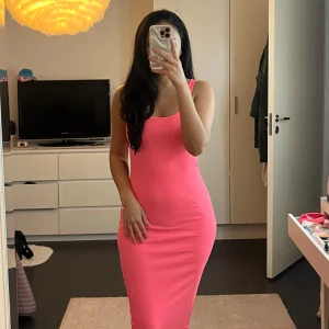 Rosa tight klänning - Säljer en snygg rosa klänning med tight passform. Klänningen är ärmlös och har en enkel design som framhäver figuren. Perfekt för en somrig look!