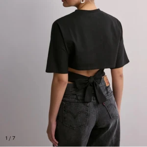 Svart croppad topp med knyt - Knyt tröja från Nelly ! Har inte andvändigt den än. Den är helt ny  och har fortfarande pris lappen på. Den är i storlek xs men passar även S🥰