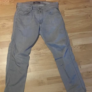 Grå jeansbyxor från Replay - Snygga grå jeansbyxor från Replay med klassisk femficksdesign och knappgylf. Byxorna har en modern passform och är perfekta för en stilren look. De är tillverkade i ett bekvämt material som ger en bra passform hela dagen.
