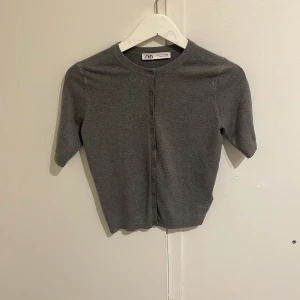 Grå kofta från Zara - Säljer en fin grå kofta från Zara med knappar framtill. Koftan har korta ärmar. Säljer för att jag inte andvänder. Pris kan diskuteras.💕