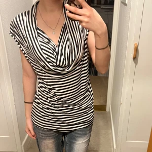 Randig topp - Säljer en svartvit randig topp. Toppen har en loose passform och är ärmlös, vilket gör den perfekt för varmare dagar. Materialet är mjukt och bekvämt.