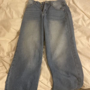 Blå jeans med vid passform - Snygga blå jeans med en avslappnad, vid passform. De har en klassisk femficksdesign och en dragkedja framtill. Perfekta för en casual look.