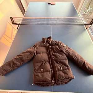 Moose Knuckles jacka utan luva - Säljer en Moose Knuckles jacka utan luva  har en hög krage och knappar framtill. Perfekt för kyliga dagar när du vill hålla stilen. 🧥