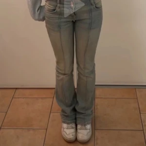 Blå bootcut jeans - Snygga blå bootcut jeans med låg midja och framträdande sömmar. Perfekta för en avslappnad stil. De har en klassisk femficksdesign och en dragkedja med knappstängning.