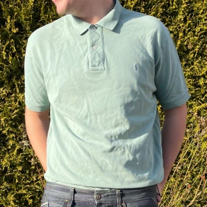 Grön pikétröja från Ralph Lauren - Säljer en stilren grön pikétröja från Ralph Lauren i storlek L. Tröjan är tillverkad i 100% bomull och har en klassisk krage med knappar. Perfekt för en avslappnad och snygg look.