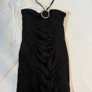 Svart y2k halterneckklänning från Gina tricot - Säljer denna svarta, korta y2k halterneck-klänningen. Kort i passformen och formar sig fint efter kroppen. Storlek M men passar som en S.