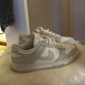 Nike Dunk i vitt och grått - Snygga Nike Dunk sneakers i en stilren kombination av vitt och ljusgrått. I storlek 37.5.