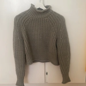 olivgrön stickad polotröja - Säljer en mysig olivgrön stickad polotröja med ribbad design. Perfekt för kyliga dagar med sin höga krage och långa ärmar. Tröjan har en skön och avslappnad passform. Den ser helt ny ut och är nästan oanvänd. Storlek: XS