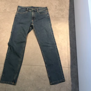 Blå jeans från H&M - Snygga blå jeans från H&M i en klassisk straight fit. Tillverkade av 20% återvunnen bomull, vilket gör dem både stiliga och miljövänliga. Perfekta för en avslappnad look med sina fem fickor och traditionella dragkedja och knappstängning.