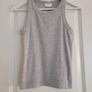 Grå ribbad linnetopp från Gina Tricot - Säljer en stilren grå ribbad linnetopp från Gina. Perfekt för varma dagar eller som lager under en jacka. Toppen är ärmlös och har en klassisk rund halsringning. Ett måste i garderoben för en enkel och snygg look.