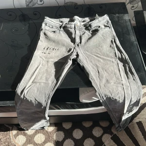 Grå jeansbyxor  - Snygga grå jeansbyxor med en klassisk femficksdesign. De har en rak passform och är perfekta för en avslappnad stil. Byxorna har en dragkedja och knapp framtill.