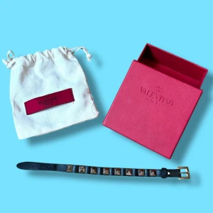 Valentino armband - Säljer ett riktigt snyggt armband från Valentino i svart skinn med silverfärgade pyramidformade nitar. Justerbart spänne i silverfärg. Kommer med originalpåse och box. Funkar för både tjejer och killar. Helt okej skick. Vid minsta fråga eller fundering, tveka inte på att höra av dig🤝 