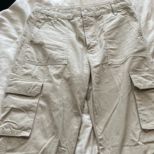 Beiga cargobyxor - Ett par fina cargobyxor med fina ditaljer, med fickor på benen. Raka i modellen.