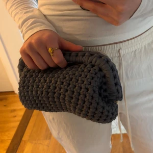 Grå handvirkad clutch / väska - Säljer en grå handvirkad clutch / handväska som jag har virkat! Väskan är i ett mjukt garn och är väldigt rymlig! Kan bäras i handen som en clutch eller bäras i handtaget.  Kan Även Göra Andra Färger / storlekar💕 skriv för mått, olika på vissa 💕