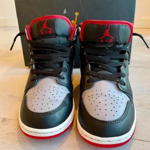 Nike Air Jordans 1 Mid  - Säljer ett par Nike air jordans 1 mid med färgen: Black/cement Gray-fire red. Priset kan diskuteras, jag är öppen för förslag.