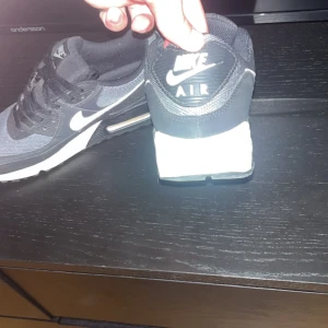 Nike Air Max 90 svart/vit - Säljer ett par klassiska Nike Air Max 90 i svart och grått med vita detaljer och sula. Riktigt feta nu till sommaren🙌🏼☀️