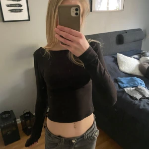 Svart croppad långärmad topp - Säljer en svart, croppad långärmad topp med tight passform. Enkel och stilren design utan synliga detaljer eller mönster. Perfekt att matcha med jeans eller kjol. Öppen i ryggen.