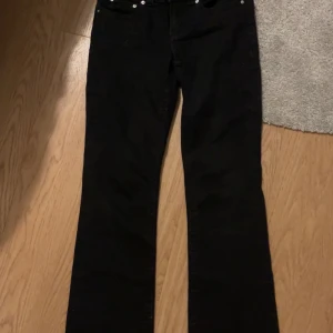 Svarta bootcut jeans från Perfect Jeans - Svarta jeans från Perfect Jeans med klassisk femficksdesign och bootcut passform. Byxorna har silverfärgade knappar och detaljer, och är tillverkade i ett stretchigt jeanstyg som sitter snyggt över höfterna och låren.