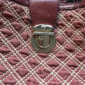 Quiltad handväska från Marc Jacobs! - Säljer en snygg quiltad handväska från Marc Jacobs i vinröd färg med mönstrade sömmar och silvriga metalldetaljer. I bra skick, små skavanker men inget man tänker på. Väskan har ett klassiskt spänne framtill och rejäla handtag. Insidan är ljus med dragkedjefack.
