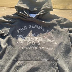 Grön hoodie från Denim & Supply Ralph Lauren - Säljer en grön hoodie från Denim & Supply Ralph Lauren med tryck framtill. Tröjan har huva, magficka och långa ärmar. Perfekt för en avslappnad stil och enkel att matcha. Är i grön färg, kanske inte syns i solljuset, men om tydligare bilder efterfrågas är det bara att skicka ett meddelande. Storlek M, har en defekt på innersidan av mudden men inget som syns. Är lös i passformen neråt, även uttöjd i midjemudden. Vid frågor eller funderingar skicka ett meddelande💫