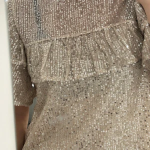 Champagnefärgad paljett blus från Lindex - Superfin champagnefärgad blusfrån Lindex täckt med glittriga paljetter med volang detaljer! Stockholm stils blus. Passar den som är XS-XXS. använd 2 gånger.